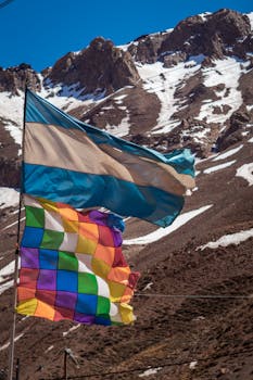 Vibrant cultural flags against a snowy mountain backdrop in the Andes.