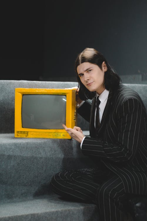 Young Man in a Suit Pointing at a Vintage TV 