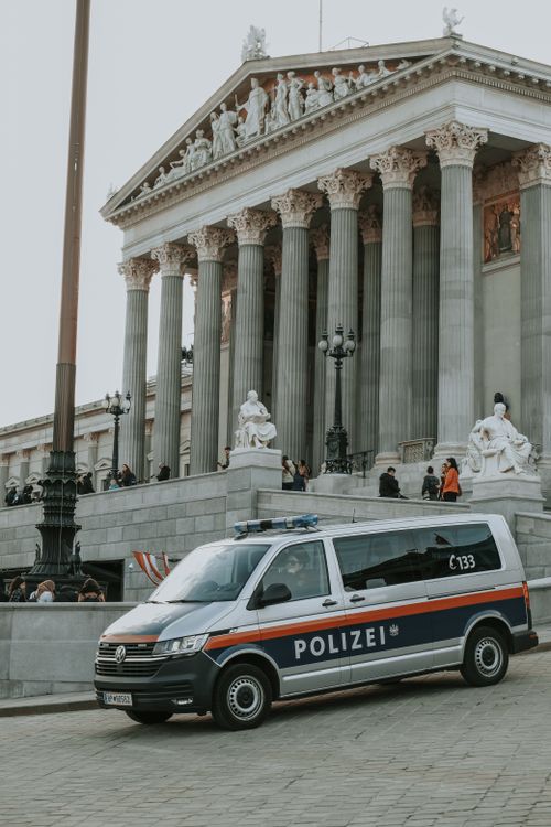 Free A police van parked outside the historic Vienna Parliament Building capturing urban city life. Stock Photo