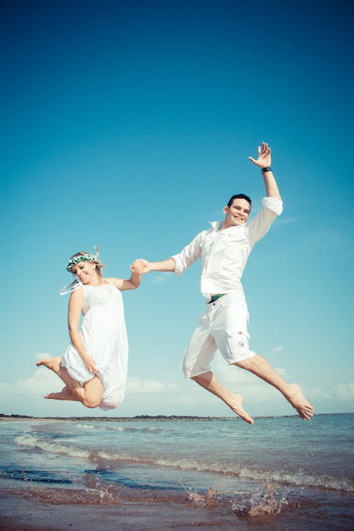Happy Bride and Groom Jumping on Seashore