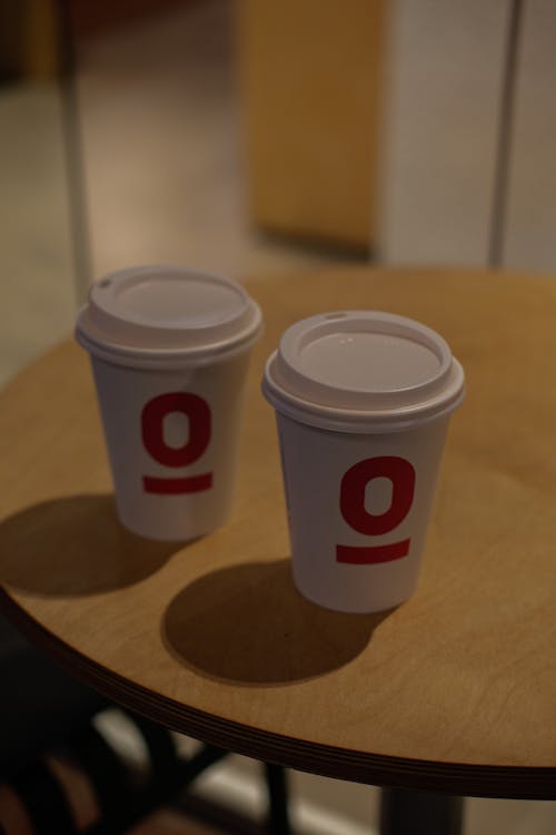 Two coffee cups sit on a table with the number 0 on them