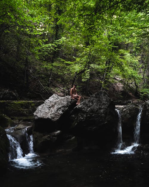 Naked Man Sitting over a Forest Waterfall