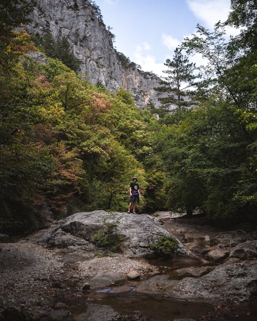 Man Standing on a Large Rock in a Canyon Valley 