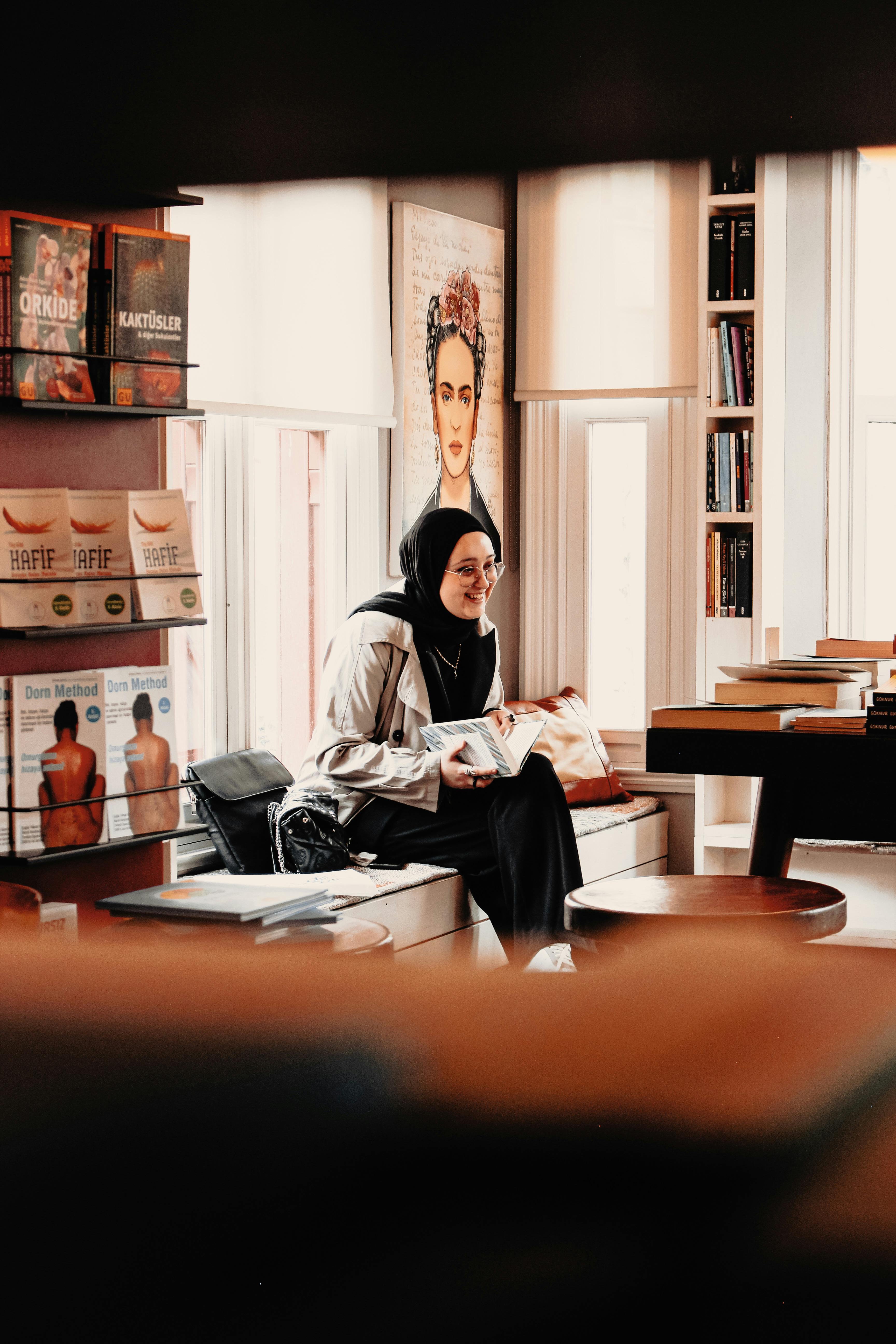 smiling woman in hijab with book in bookstore