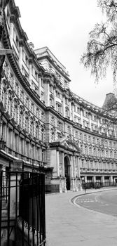 A black and white photo showcasing a neoclassical building facade in an urban setting.