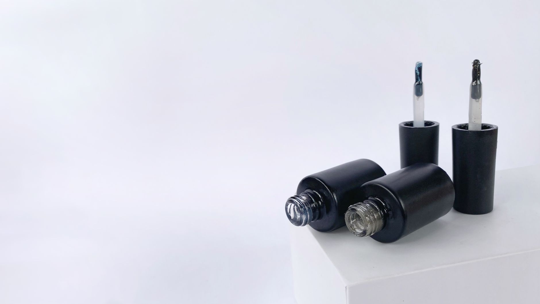 Stylish display of black nail polish bottles on a white background with ample copy space.