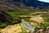 山谷间，一条河流蜿蜒穿过，两岸绿树成荫