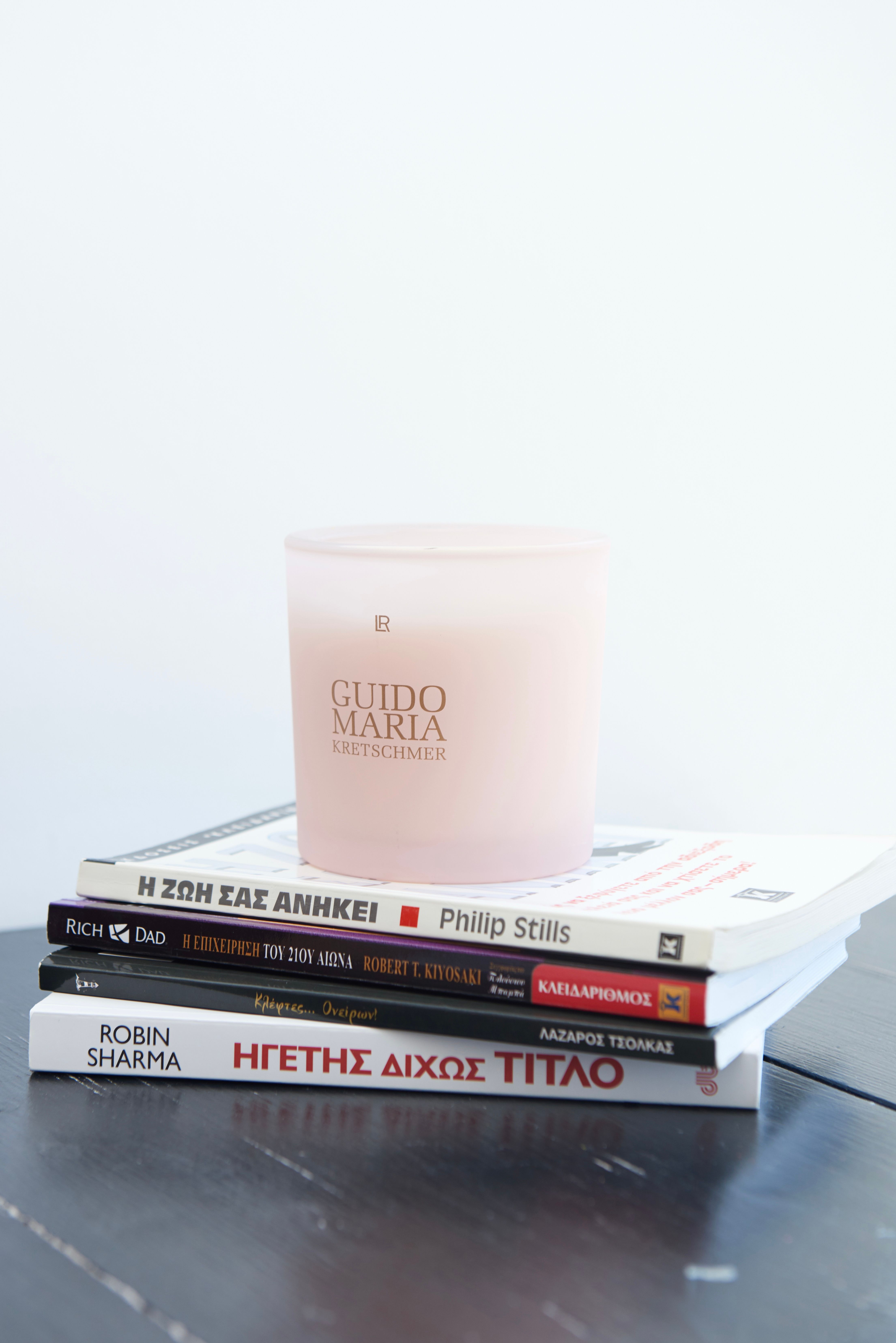 Minimalist scene with a candle on stacked books, perfect for a cozy reading atmosphere.