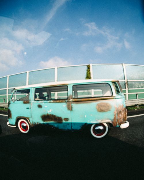 Free Old rusty campervan driving on a highway with a clear blue sky backdrop. Stock Photo