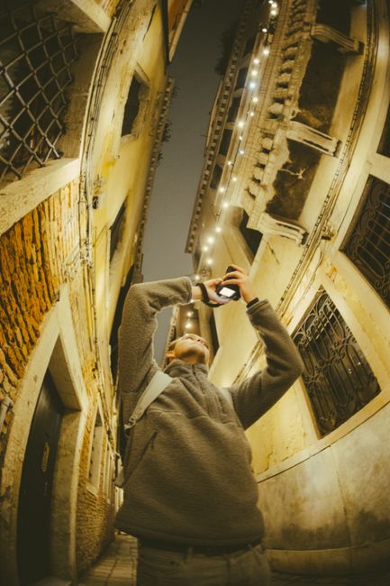 Person capturing urban architecture using fisheye lens at night.