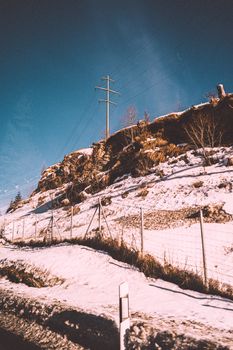 A picturesque snowy hillside with power lines under a clear winter sky.