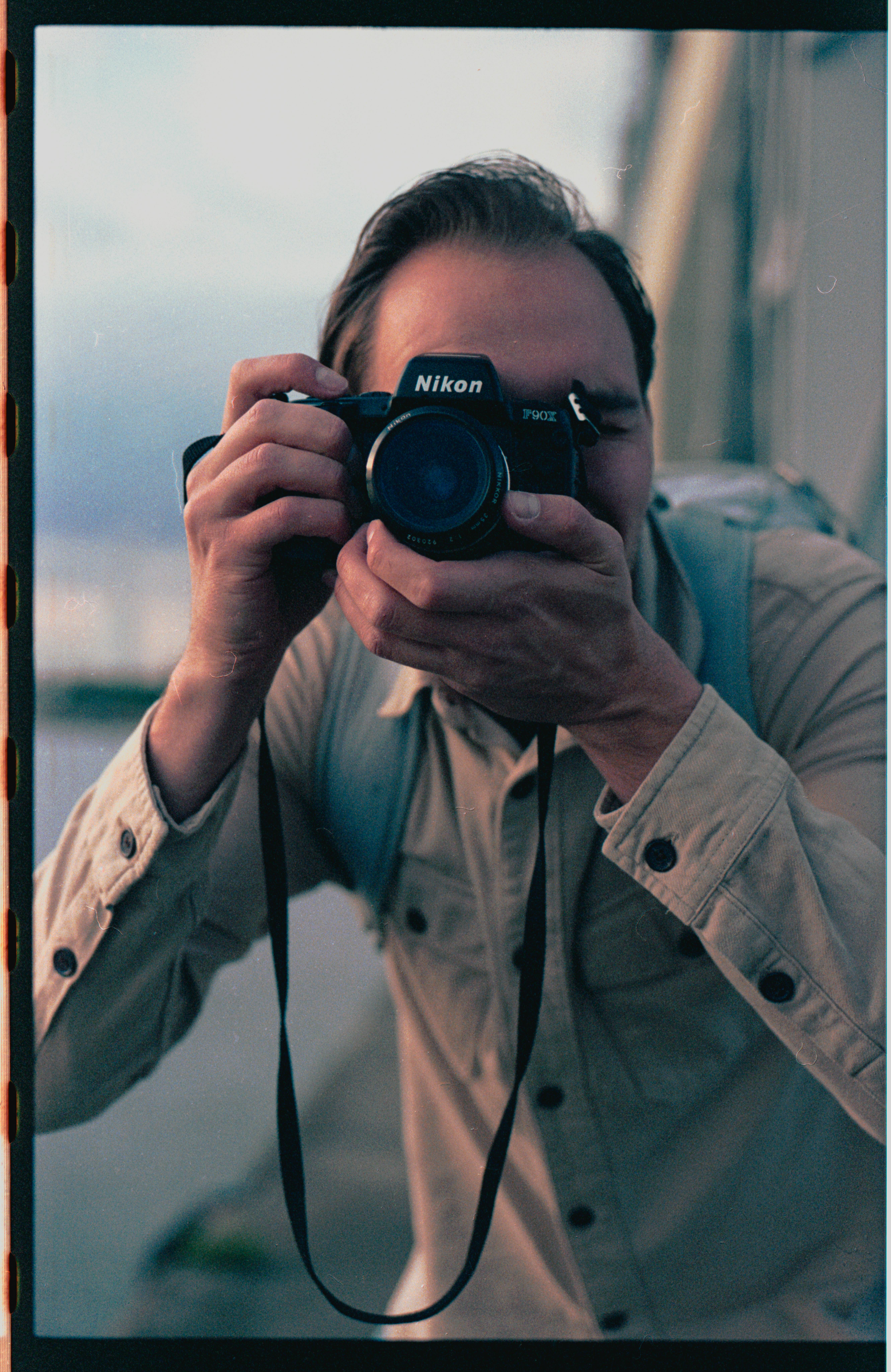 Man with Nikon camera capturing a moment outdoors with a film effect.