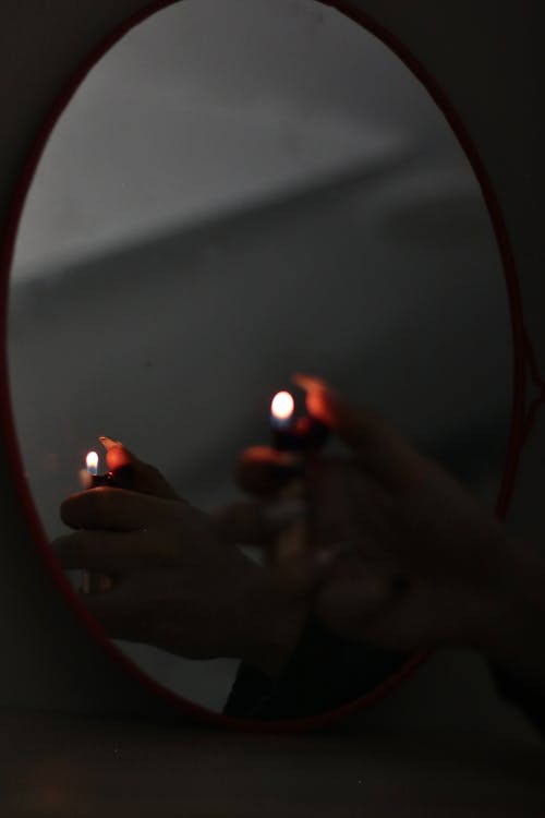 Close-up of Woman Hand with Lighter near Mirror