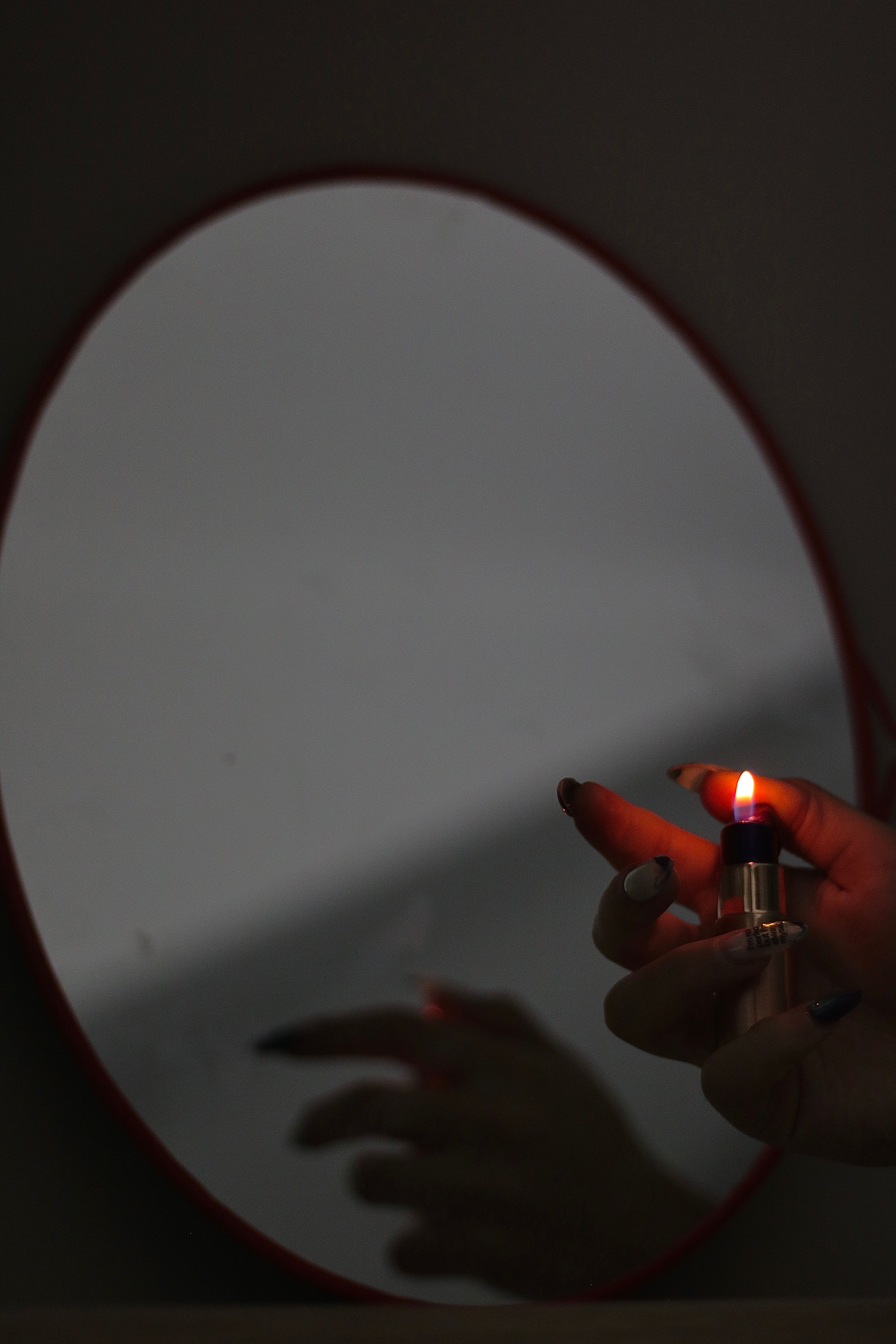 Artistic photo of a hand lighting a flame in front of a mirror, evoking introspection.