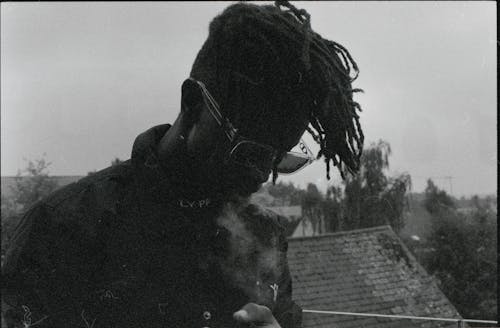 Black and White Picture of a Man with Dreadlocks Smoking 