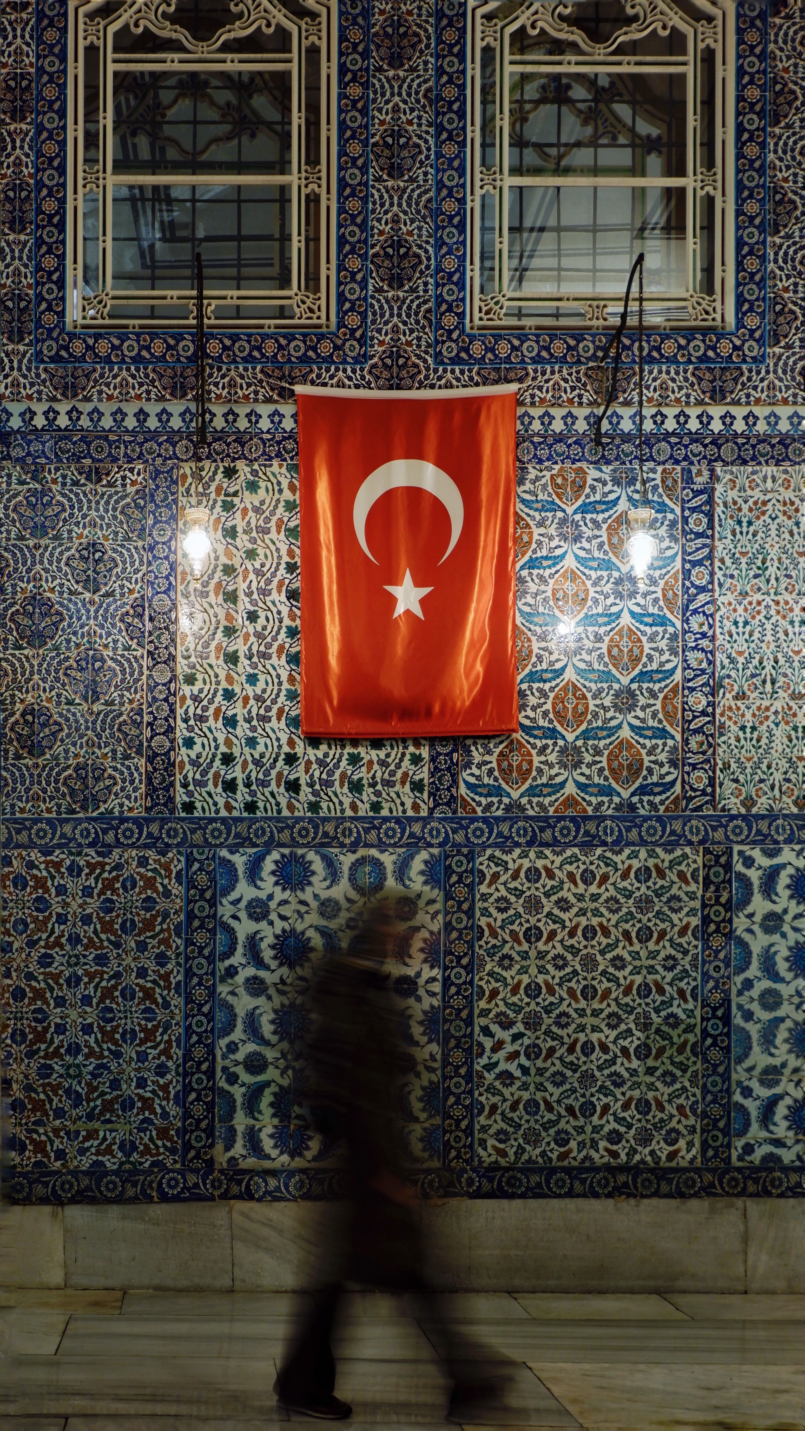Person Walking by the Wall with a Flag