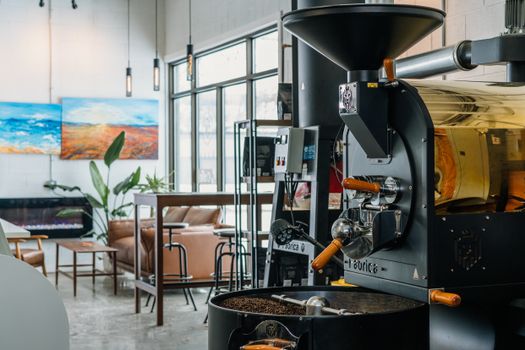 Stylish coffee shop interior featuring a professional coffee roaster and cozy seating.