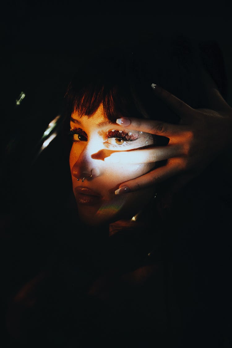 Womans Illuminated Face With Hands On Sides