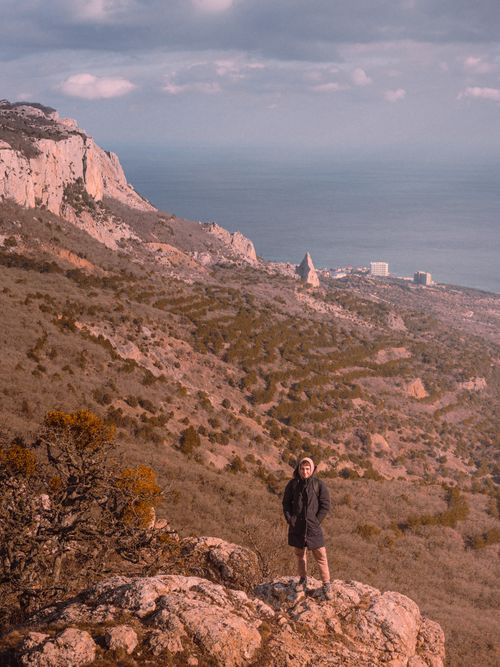 Free Scenic aerial view of the Sevastopol coastline with a solitary person standing on rocky terrain under cloudy skies. Stock Photo
