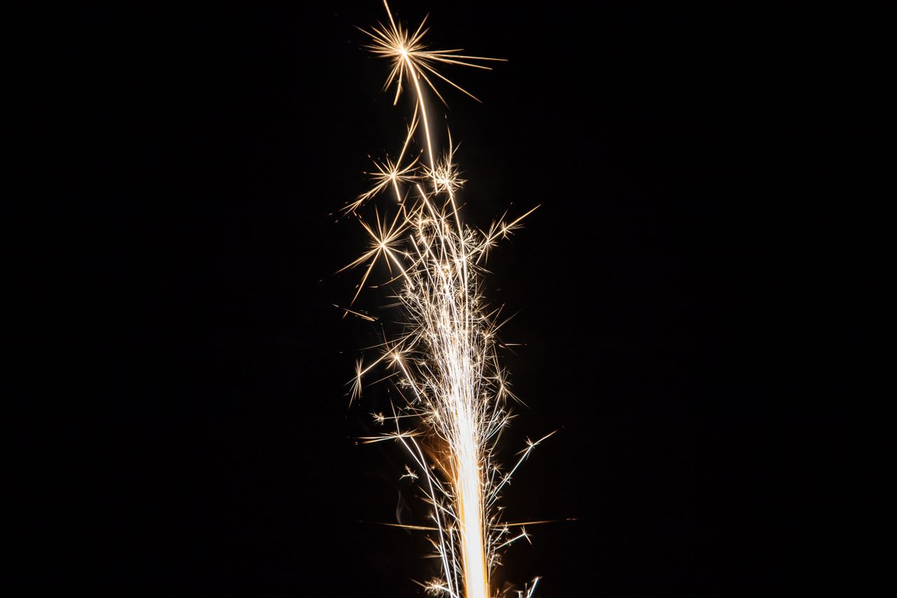 a vibrant sparkler illuminates the night sky with bright sparks and fe