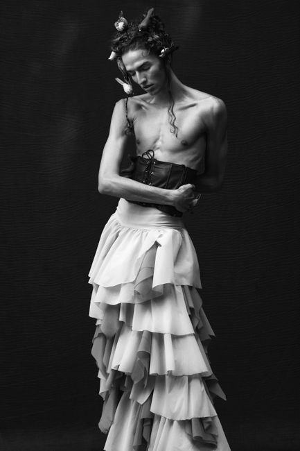 Stylish black and white portrait of a model wearing a corset and long skirt, showcasing avant-garde fashion.