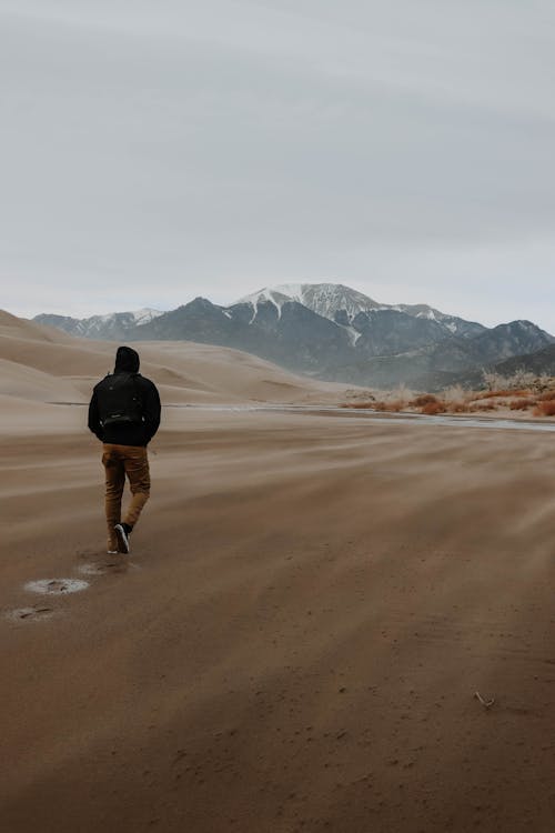 Man Hiking on Sand Dunes and Mountains Landscape 