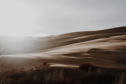 Free Beautiful desert dunes bathed in warm sunset light, highlighting soft sand patterns and serene landscape. Stock Photo