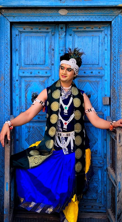 Man in a Colorful Gown Standing in front of Blue Doors