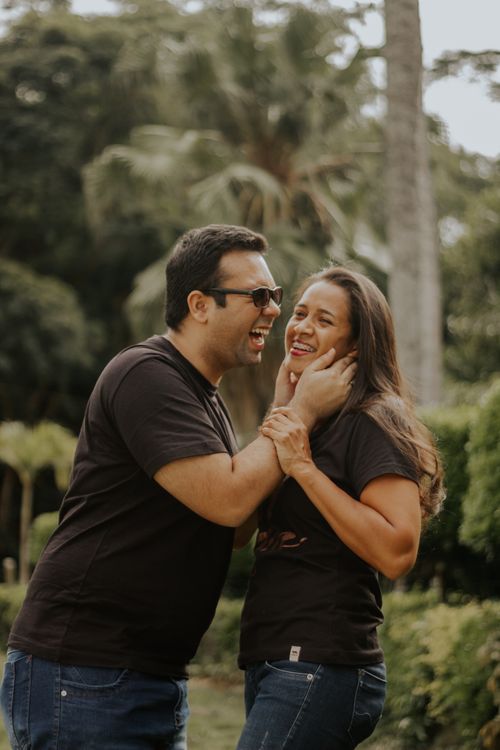 Free Cheerful couple sharing a joyful moment outdoors in a sunny park with greenery. Stock Photo
