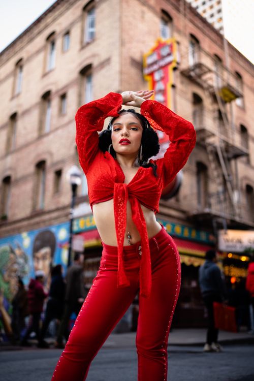 Free Fashionable woman in red posing confidently on a bustling city street. Stock Photo