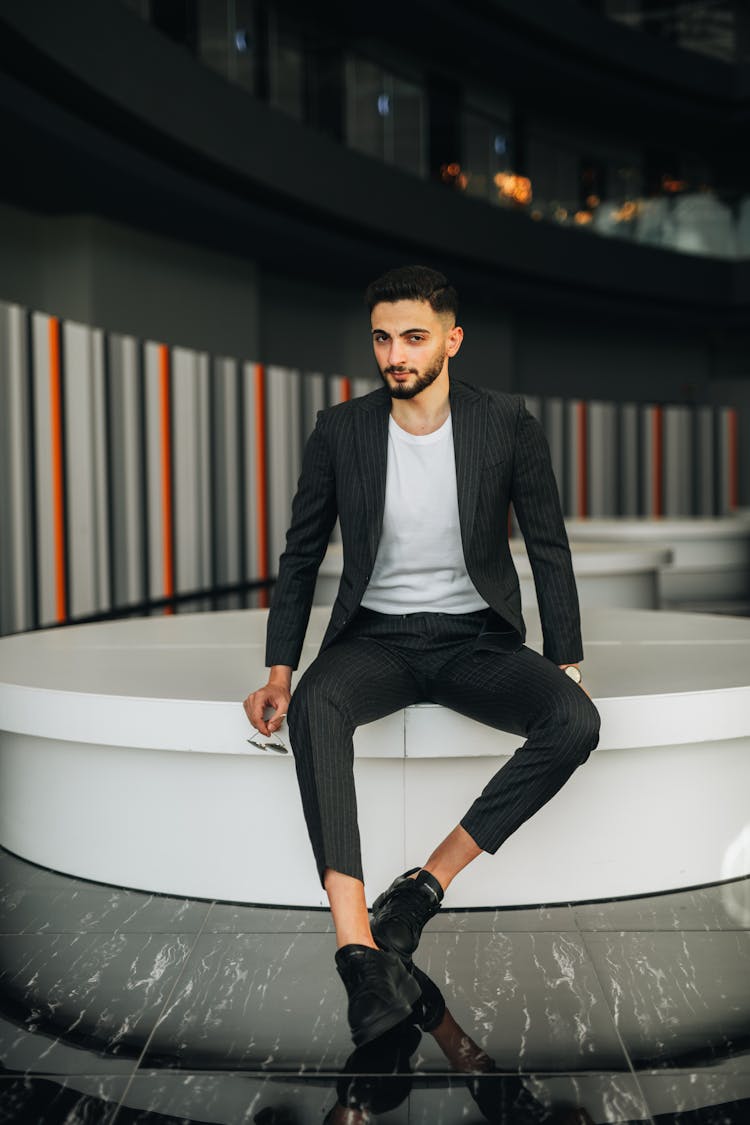 Young Man In A Suit Sitting In A Modern Room 