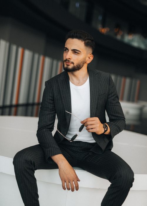 Free Confident businessman in a suit sitting indoors, exuding elegance and modern style. Stock Photo