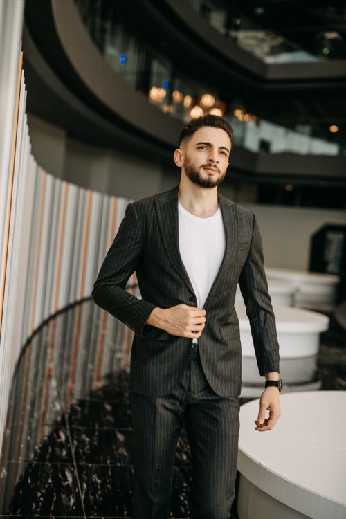 Free Confident man in pinstripe suit posing in a chic, modern setting. Stock Photo