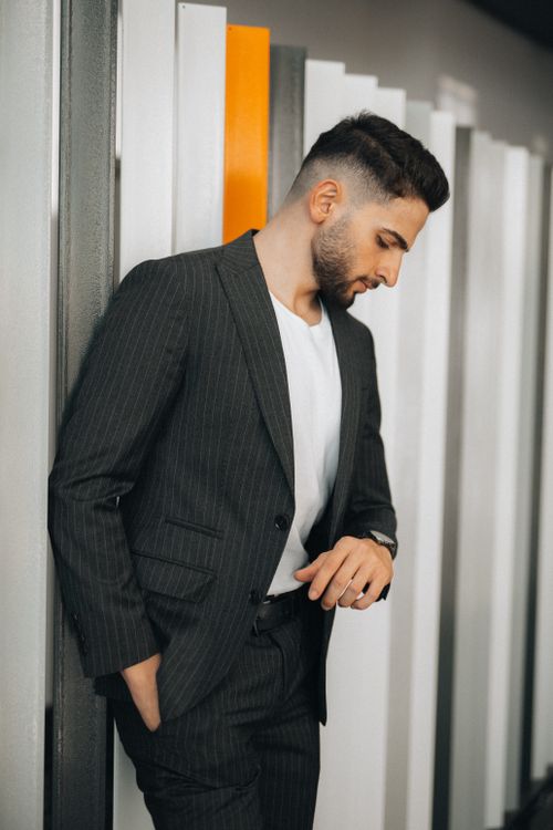 Free Stylish man in a pinstripe suit looking down indoors. Modern fashion portrait. Stock Photo