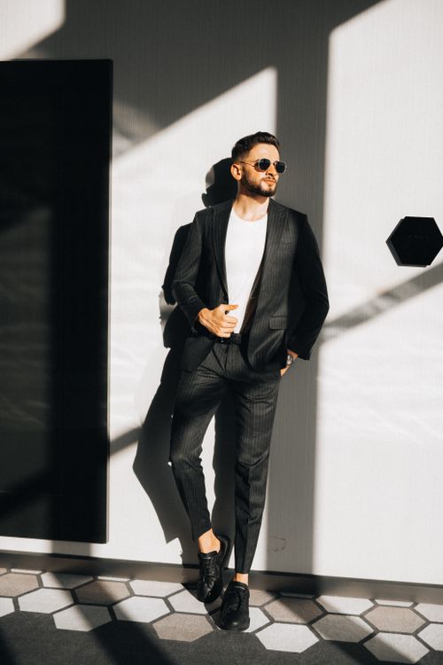 Free Man in a suit and sunglasses posing in sunlit geometric setting. Stock Photo