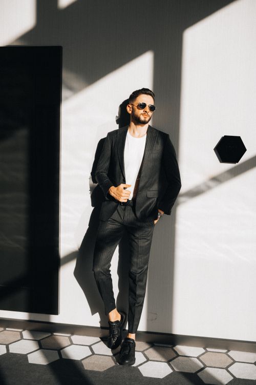 Free A fashionable man in a sleek suit poses confidently indoors with stylish sunglasses. Stock Photo