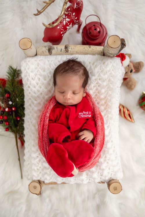 Free Peaceful baby in festive red outfit sleeps soundly, surrounded by cozy Christmas decor. Stock Photo