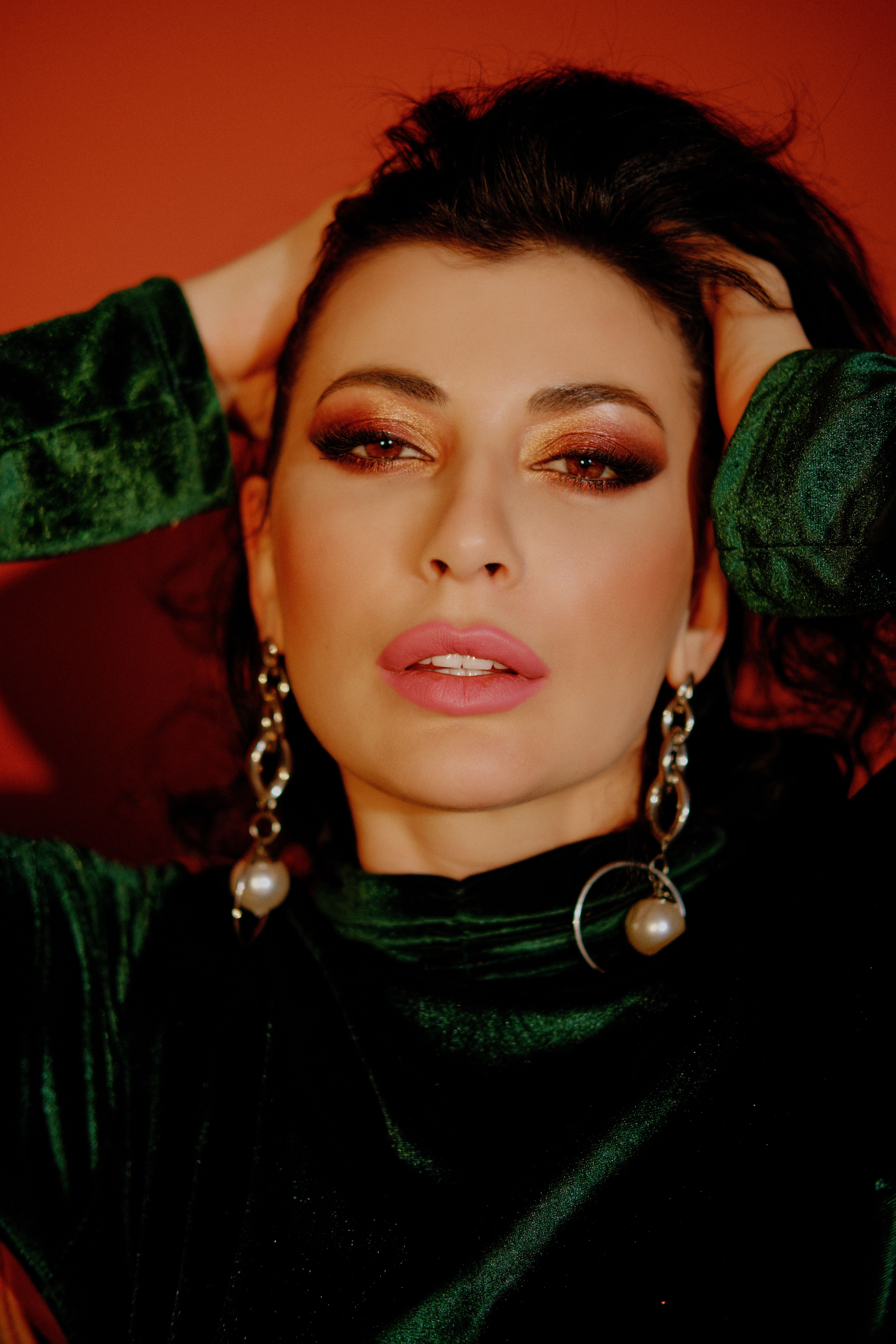 Close-up portrait of a woman in a green velvet dress with bold makeup.