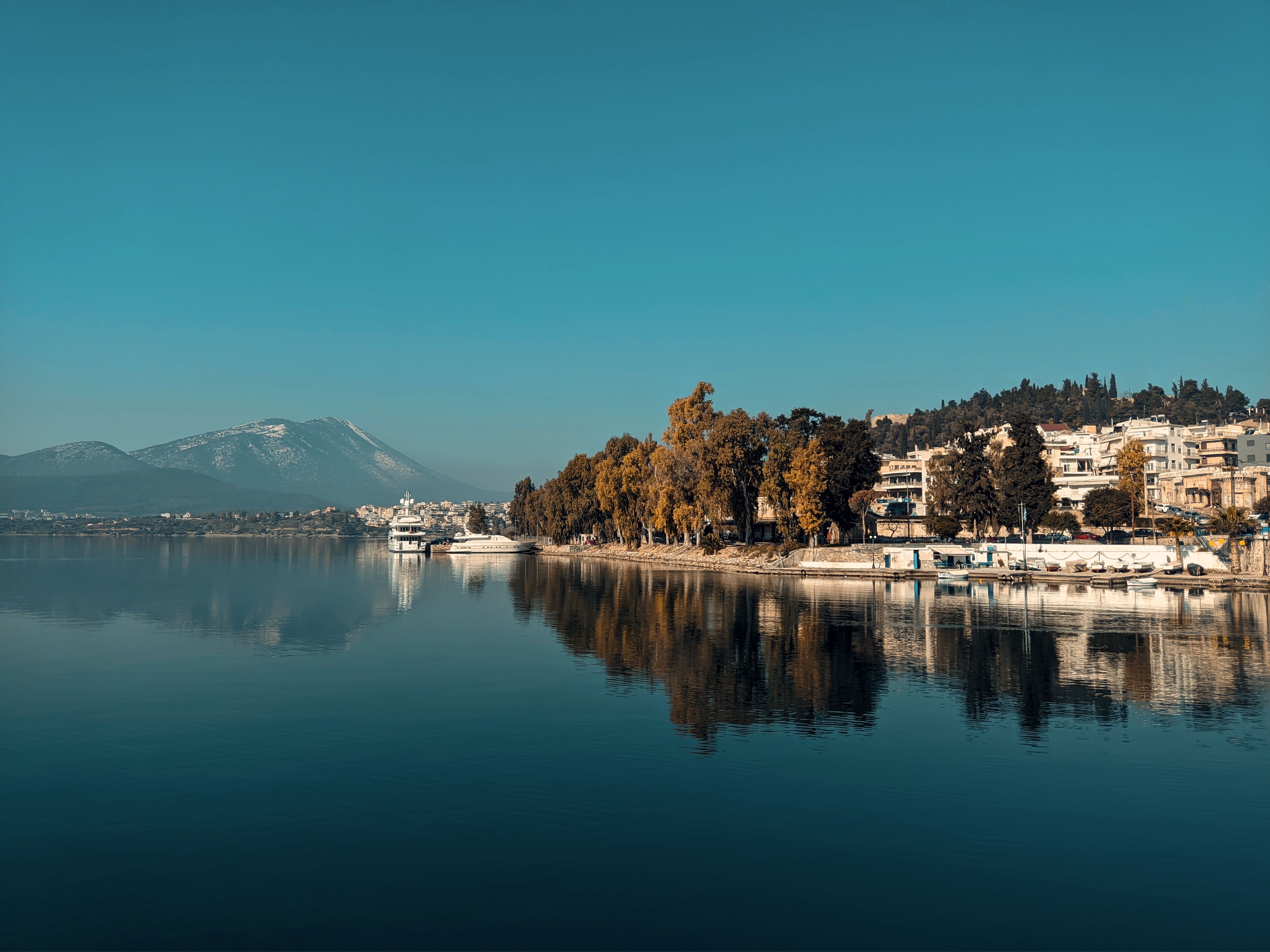 A calm lakeshore town with mountain views under a clear blue sky.