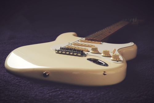 Free Close-up image of a vintage white electric guitar against a dark background, showcasing its elegant design. Stock Photo