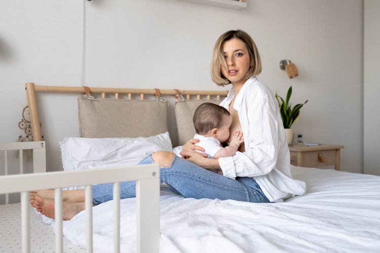 Mother Breastfeeding Her Baby On The Bed 