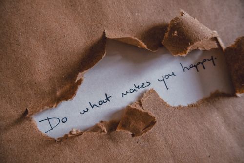Free Brown paper revealing message 'Do what makes you happy.' Stock Photo