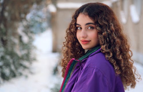 Photo of a Young Woman in a Purple Jacket Standing Outside in Winter 