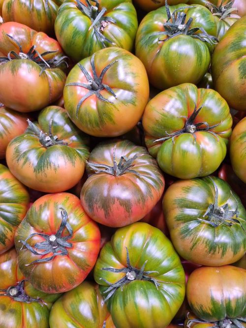 Free Fresh heirloom tomatoes with vibrant colors displayed at a market in Valencia, Spain. Stock Photo