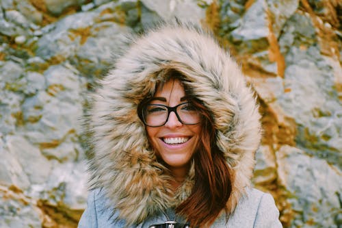 Free Woman Wearing Eyeglasses While Smiling Near Rock Formation Stock Photo