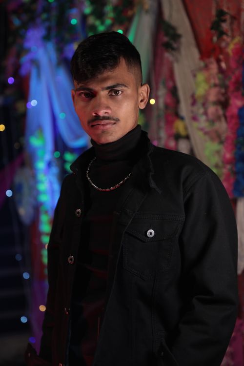 Free Portrait of a confident man with a mustache in a black jacket against a vibrant festive backdrop. Stock Photo
