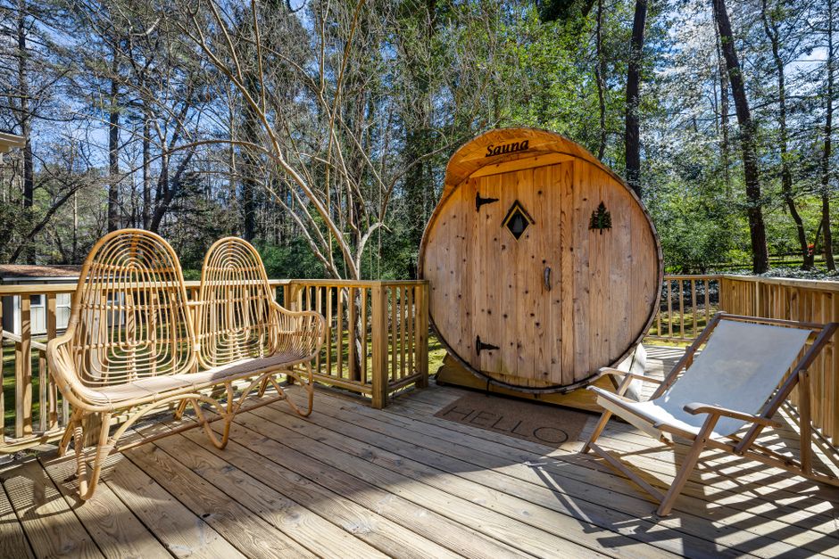 A peaceful outdoor terrace with a wooden sauna surrounded by tall trees, perfect for relaxation.