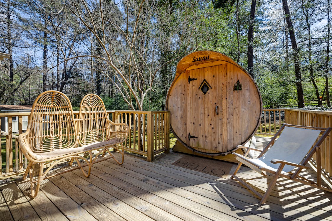 Free A peaceful outdoor terrace with a wooden sauna surrounded by tall trees, perfect for relaxation. Stock Photo