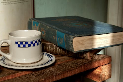 A cup of coffee sits on a table next to a book