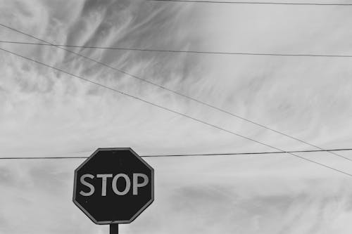 Grayscale Photography of Stop Signage Under Sky